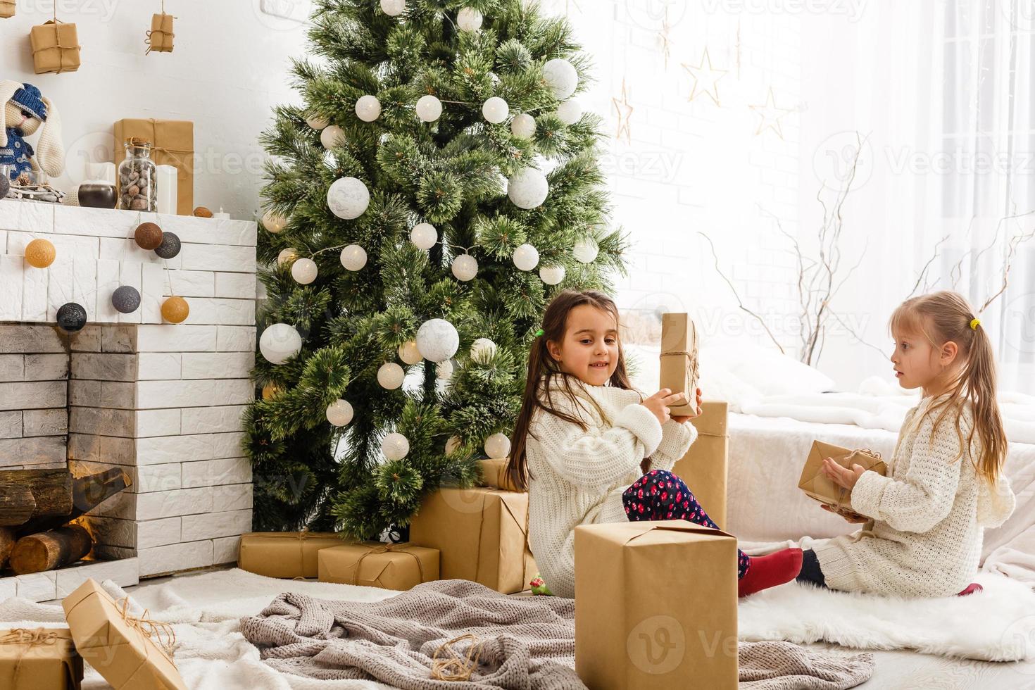 Kids little sisters hold gifts boxes interior background. What a great surprise. Small cute girls received holiday gifts. Best toys and christmas gifts. Children friends excited unpacking their gifts. photo