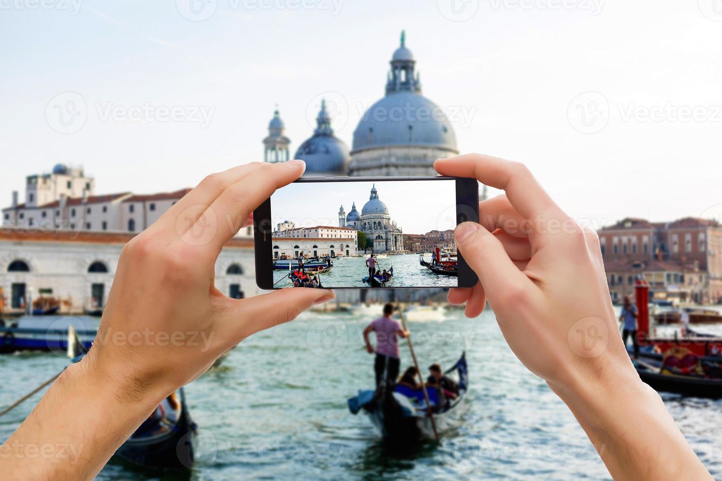 tomando fotografías en un teléfono inteligente móvil en góndola en el canal grande con una casa antigua clásica en el fondo, venecia, italia foto