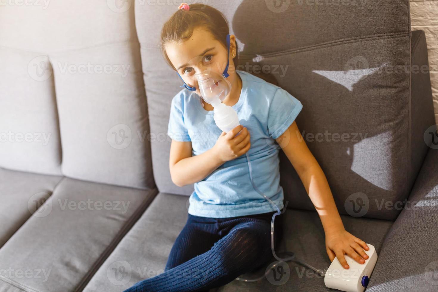 Little caucasian girl is breathing with special mask, which helps to stop asthma attack or relieve symptoms of respiratory disease. photo