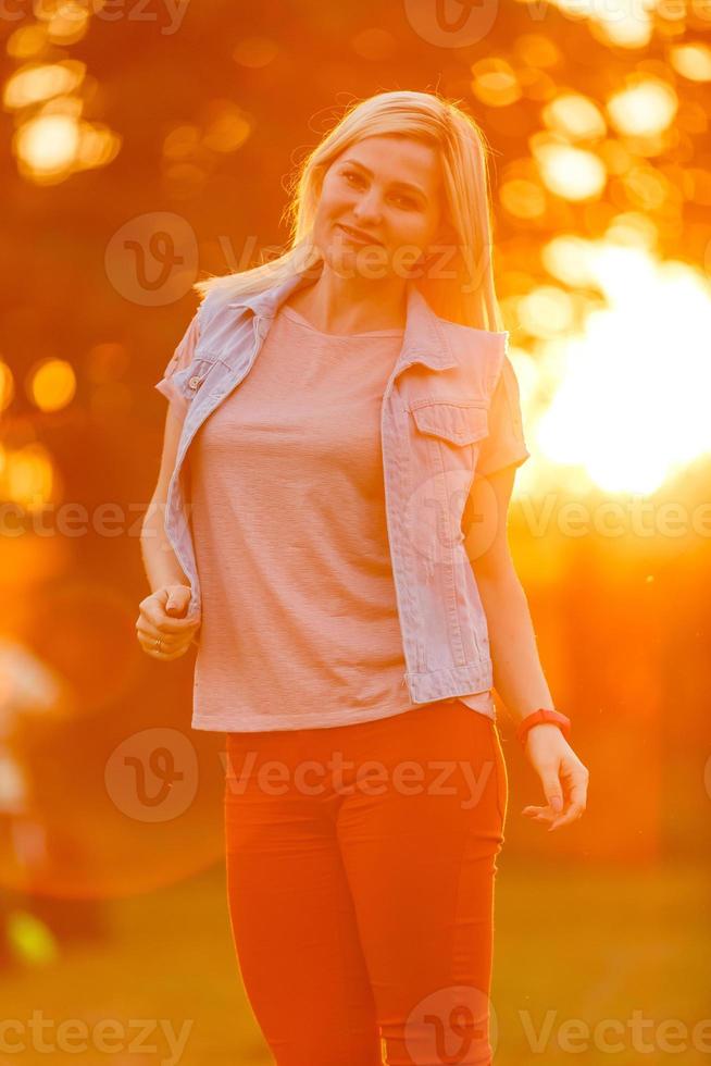 Mujer joven disfrutando de la naturaleza y la luz del sol en el campo de paja foto