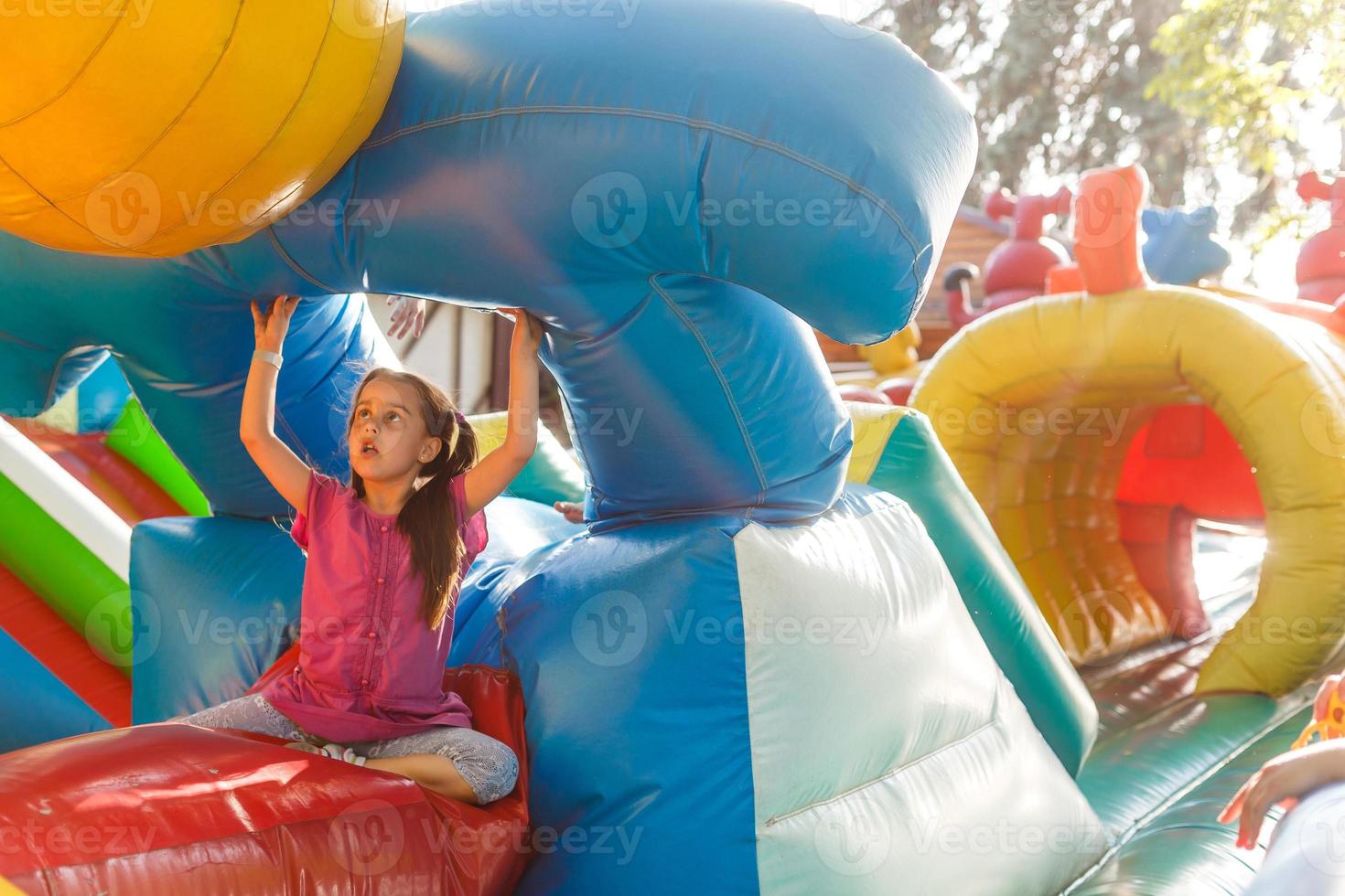 Happy little girl having lots of fun on a jumping castle during sliding. photo