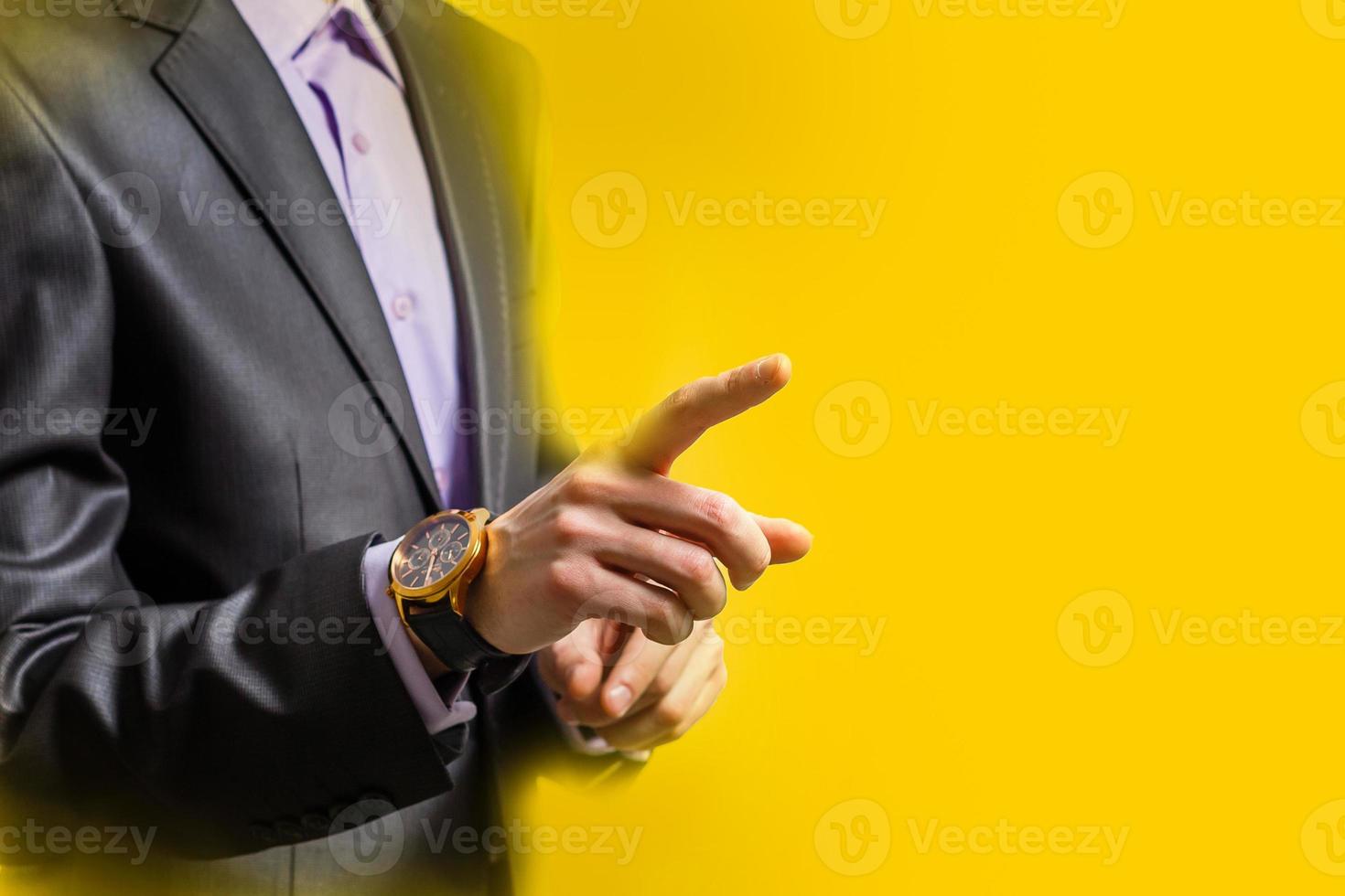 people, business and gesture concept - close up of man pointing finger to to something yellow background photo