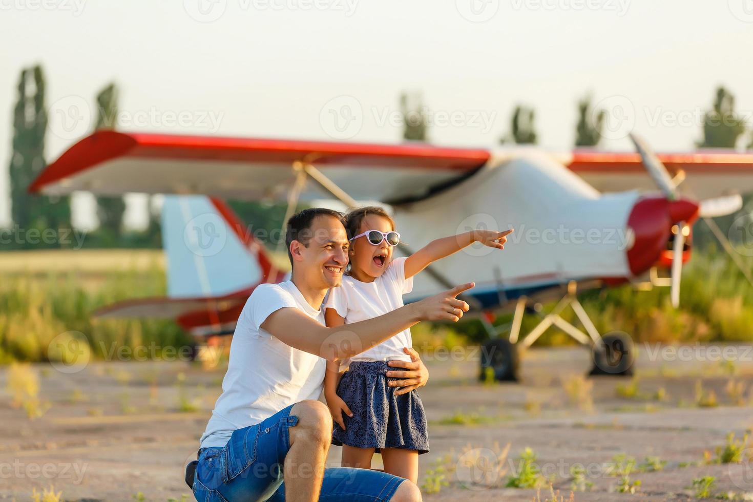 Father and daughter are happy with the plane on the meadow. photo