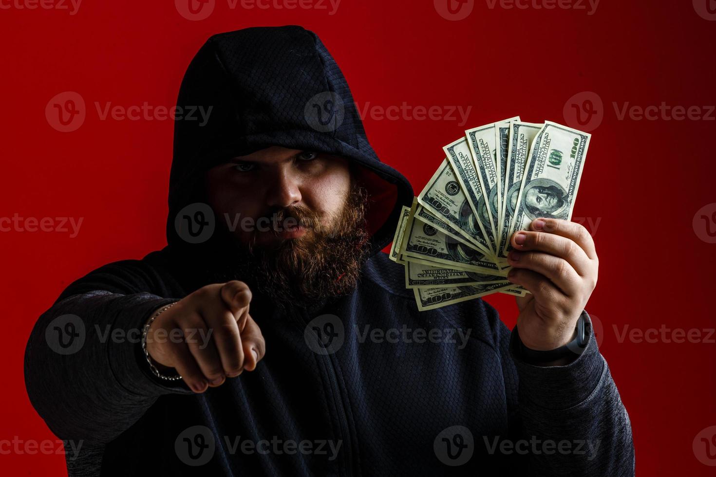 Atractivo hombre multiétnico con estilo elegante chaqueta de moda bajo la lluvia de moscas de dinero aislado en un fondo rojo vívido levantó las manos foto