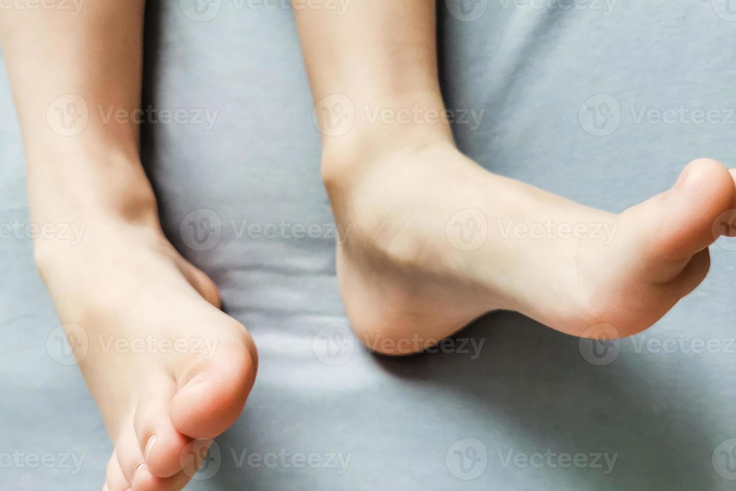 los pies descalzos de los niños. los pies descalzos del niño en una cama gris foto