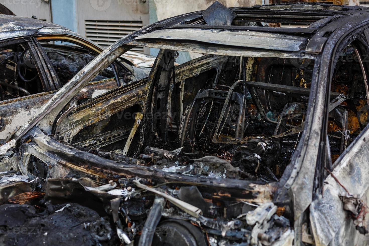 Two cars after the fire. Two burned out cars with an open hood. Arson, burnt car photo