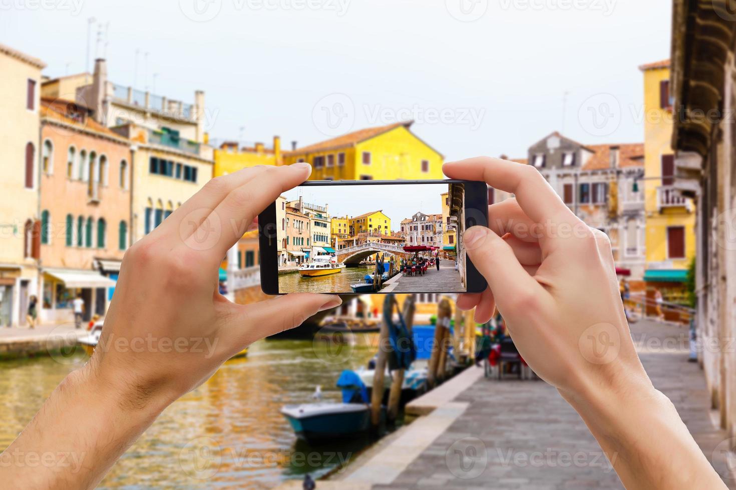 A mobile phone snapping a picture of a gondolier on his gondola in venice photo