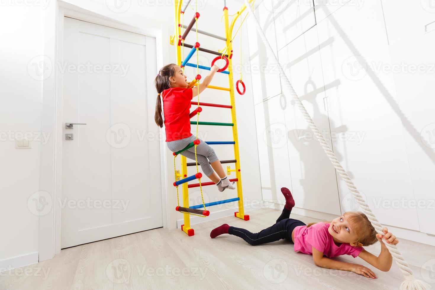 Children Activity Concepts. Little Caucasian Girls Having Stretching Exercises on Wall Bars Indoors.Horizontal Image composition photo