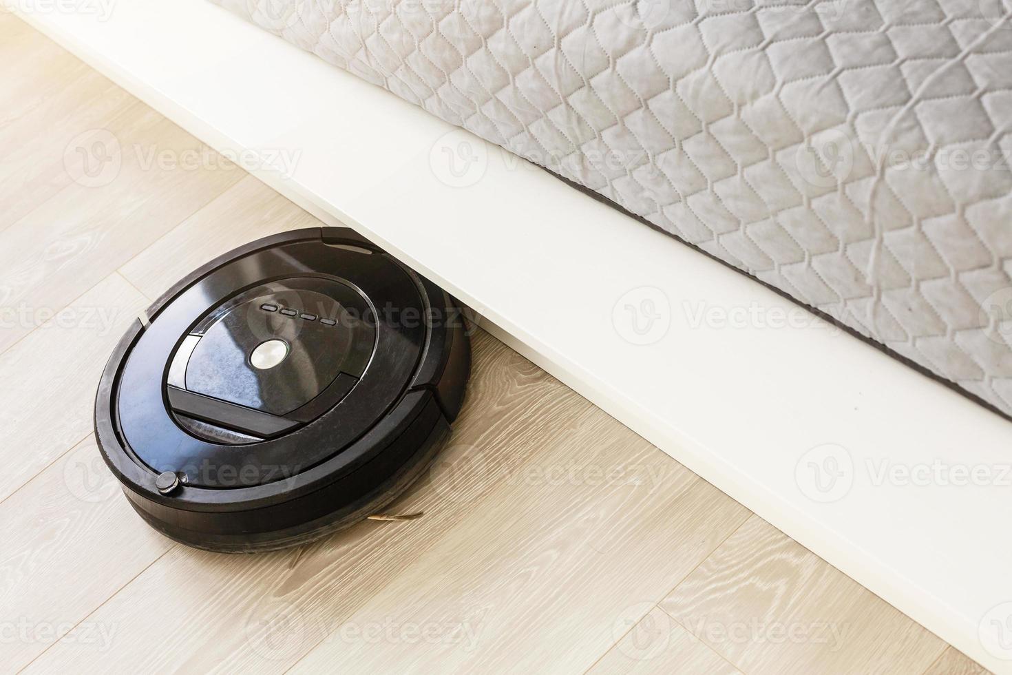 Robotic vacuum cleaner on laminate wood floor in bedroom. 16480308