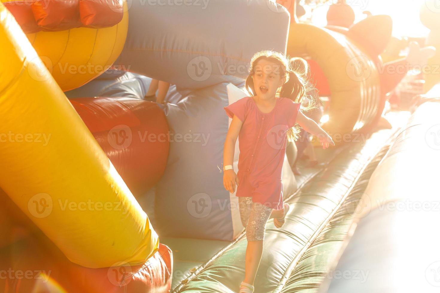 Happy little girl having lots of fun on a jumping castle during sliding photo