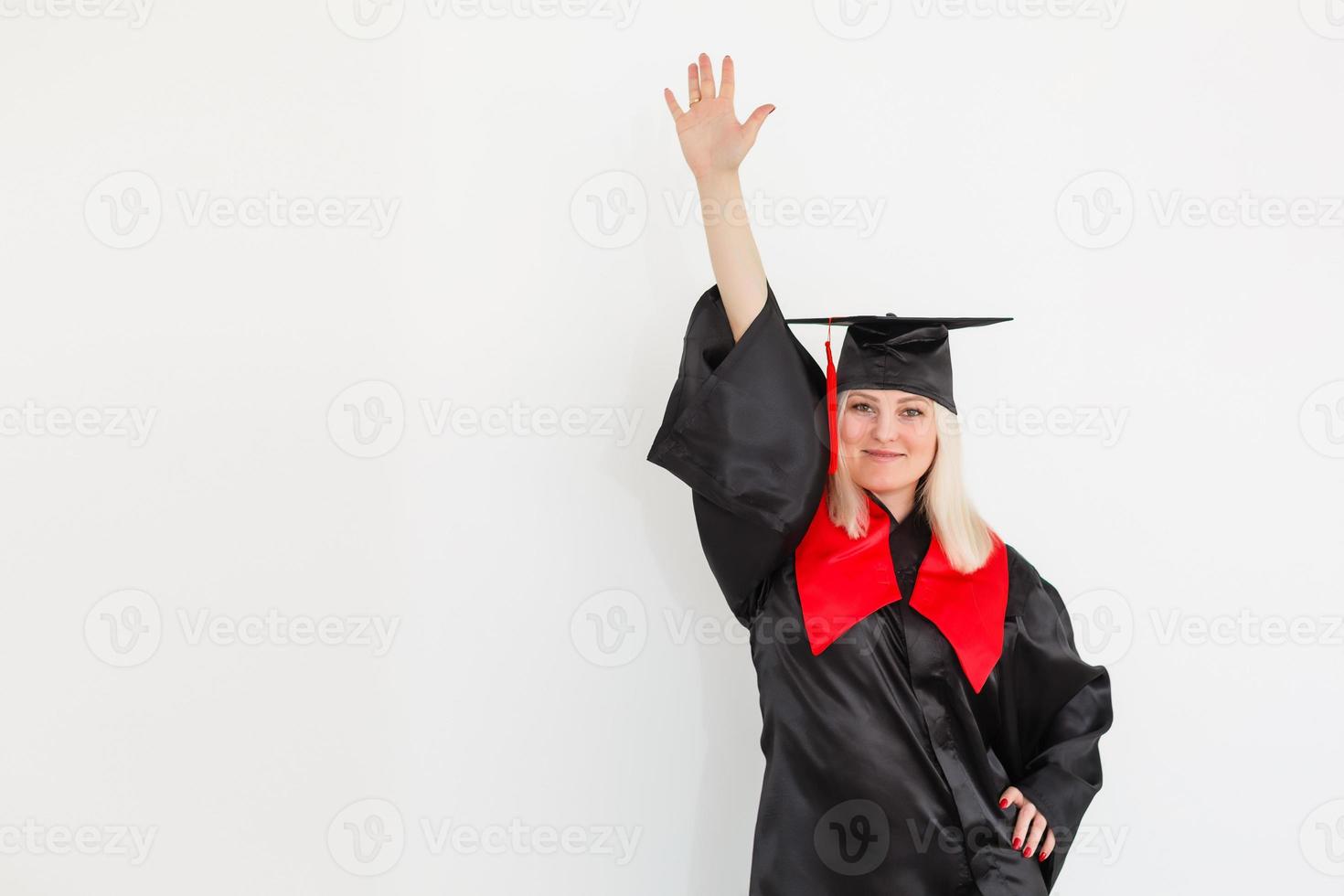 emocionada feliz estudiante graduada está de pie en el manto, sonriendo y mirando a la cámara foto