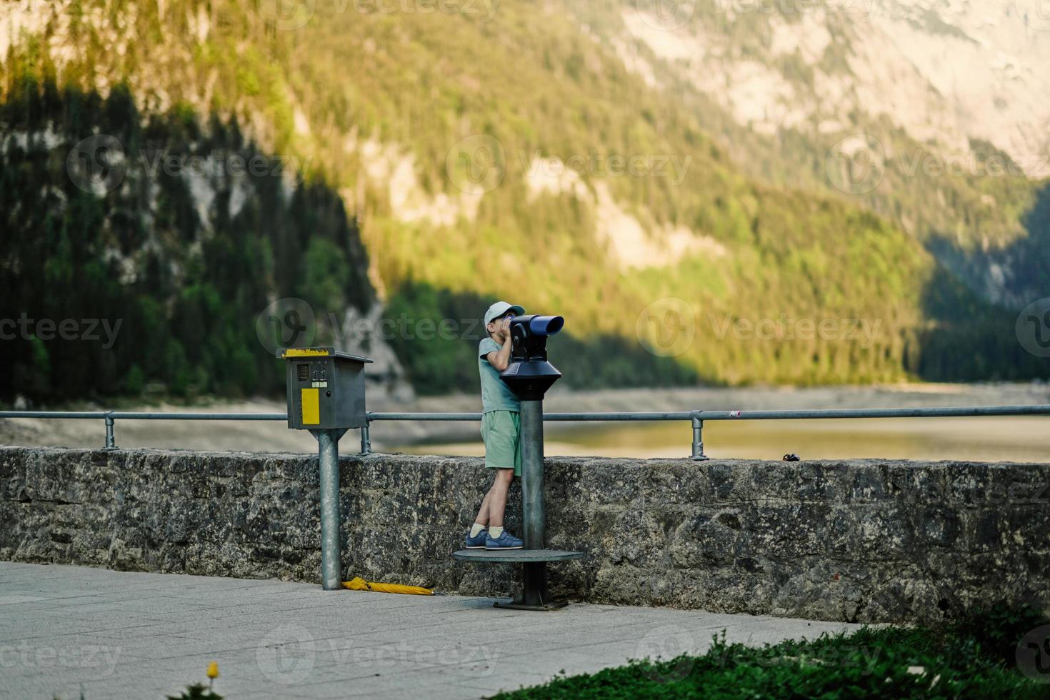 Boy look at panoramic telescope overlooking in Vorderer Gosausee, Gosau, Upper Austria. photo