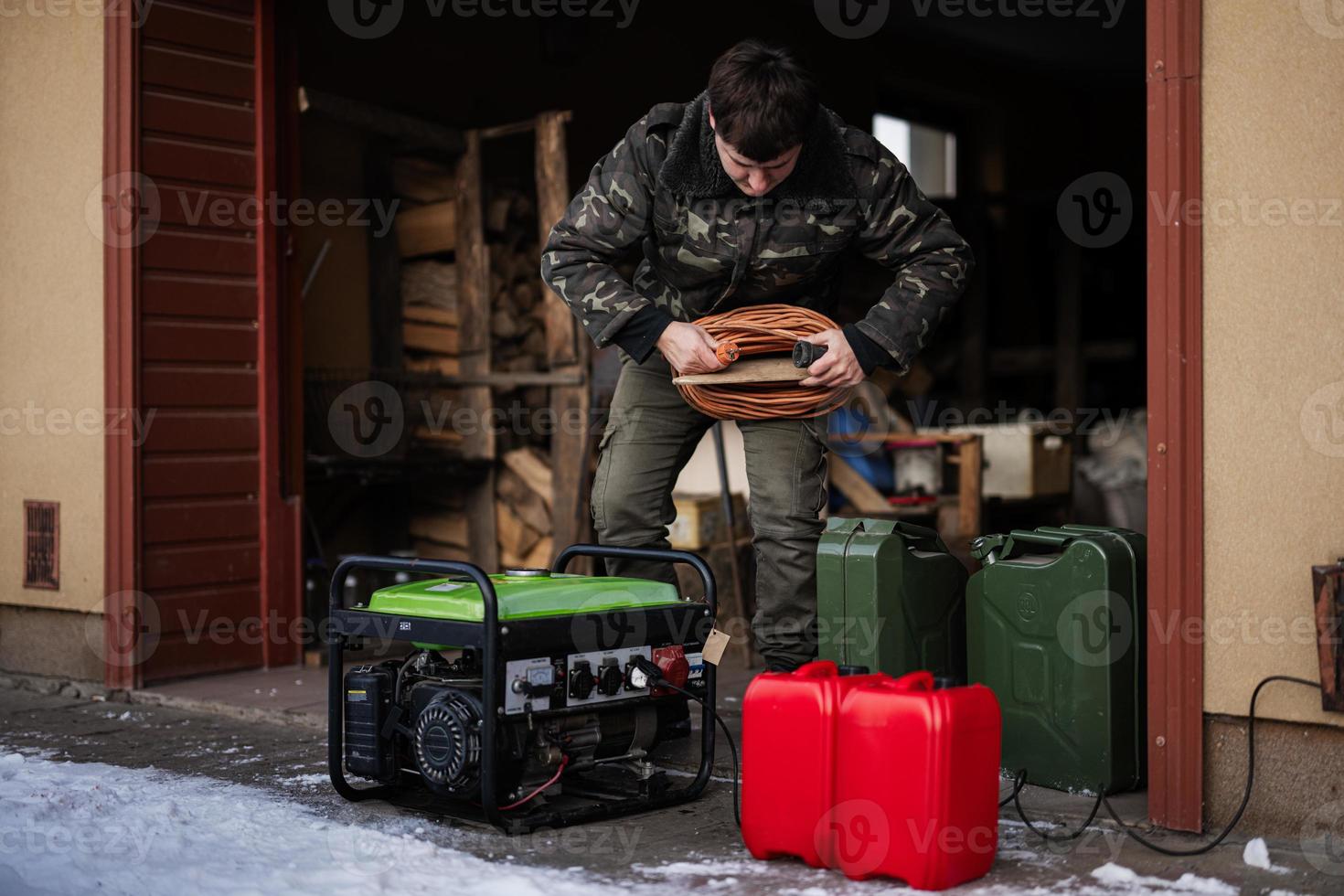 Man wear in military jacket with gasoline portable mobile backup standby generator. photo