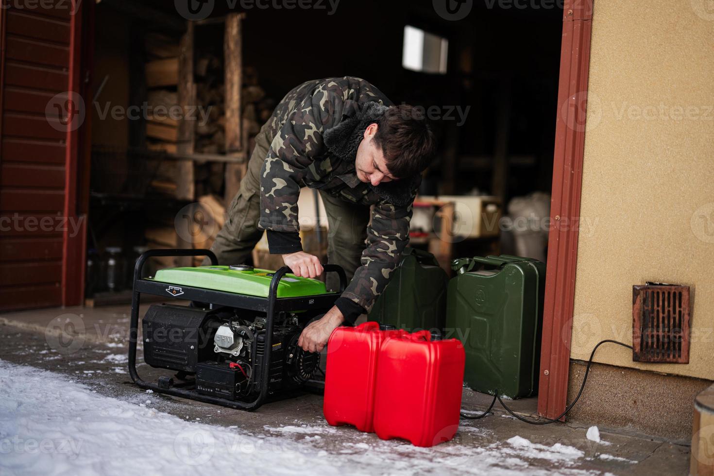 Man wear in military jacket with gasoline portable mobile backup standby generator. photo