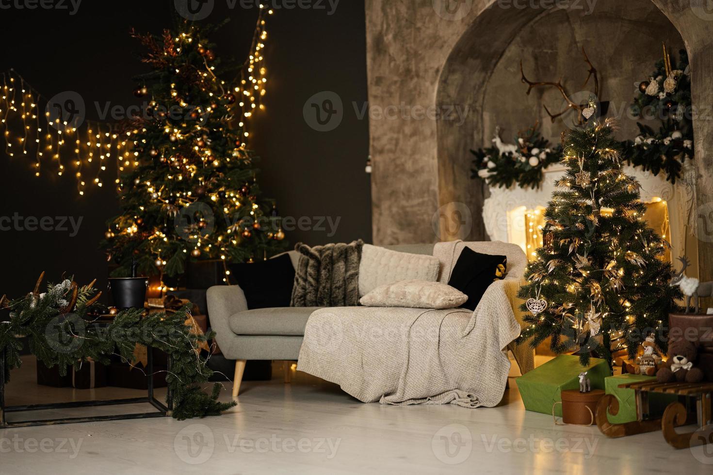 elegante interior de salón navideño con sofá, chimenea blanca, árbol de navidad y corona, regalos y decoración. foto