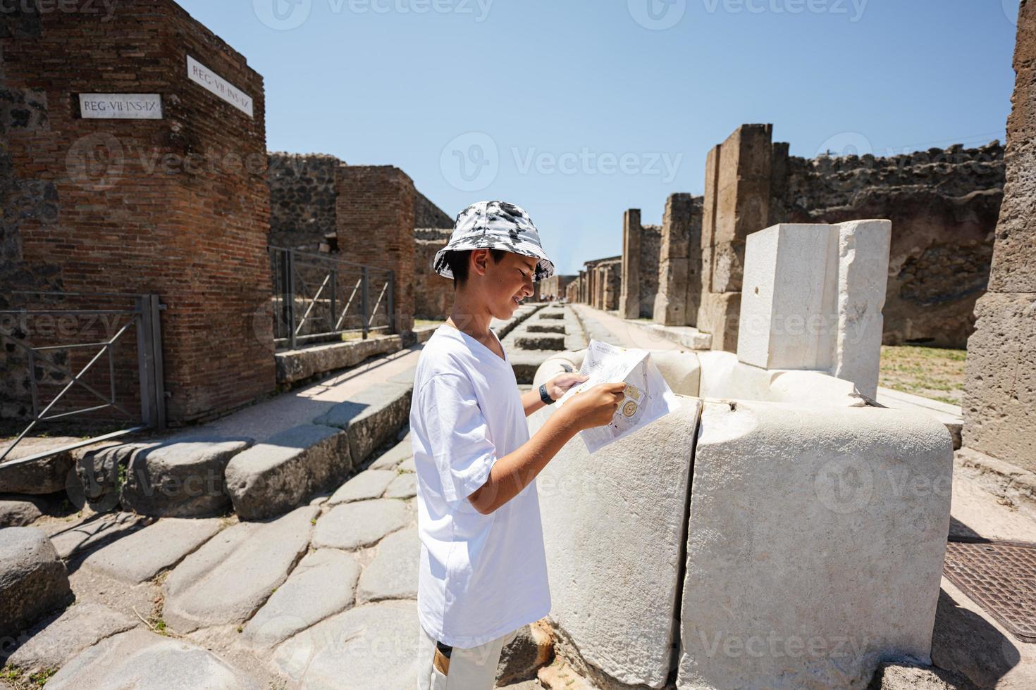 Boy tourist look at map during walking at Pompeii ancient city, Italy. photo