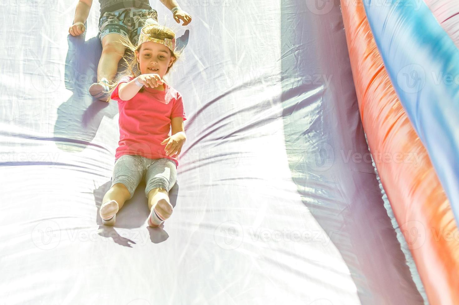 niña deslizándose por un tobogán inflable foto