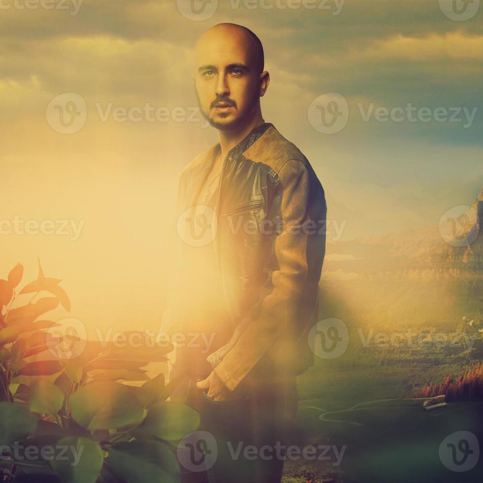 Elegant bald male in leather jacket on sunset in the mountains photo