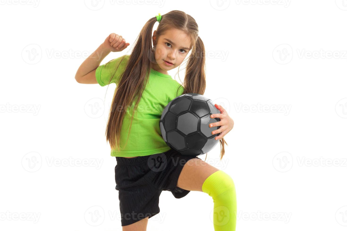 cute little girl in green uniform playing with soccer ball photo