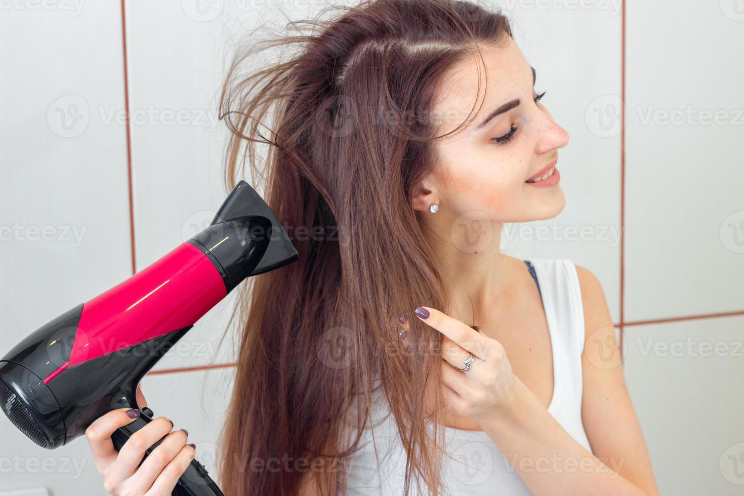 young pretty girl in white shirt dries the hair dryer photo