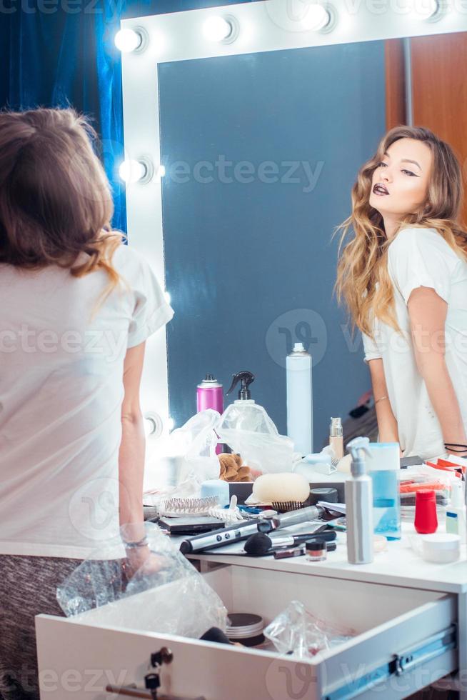 Young adorable girl with cutly hairstyle looking at the mirror in hair studio photo