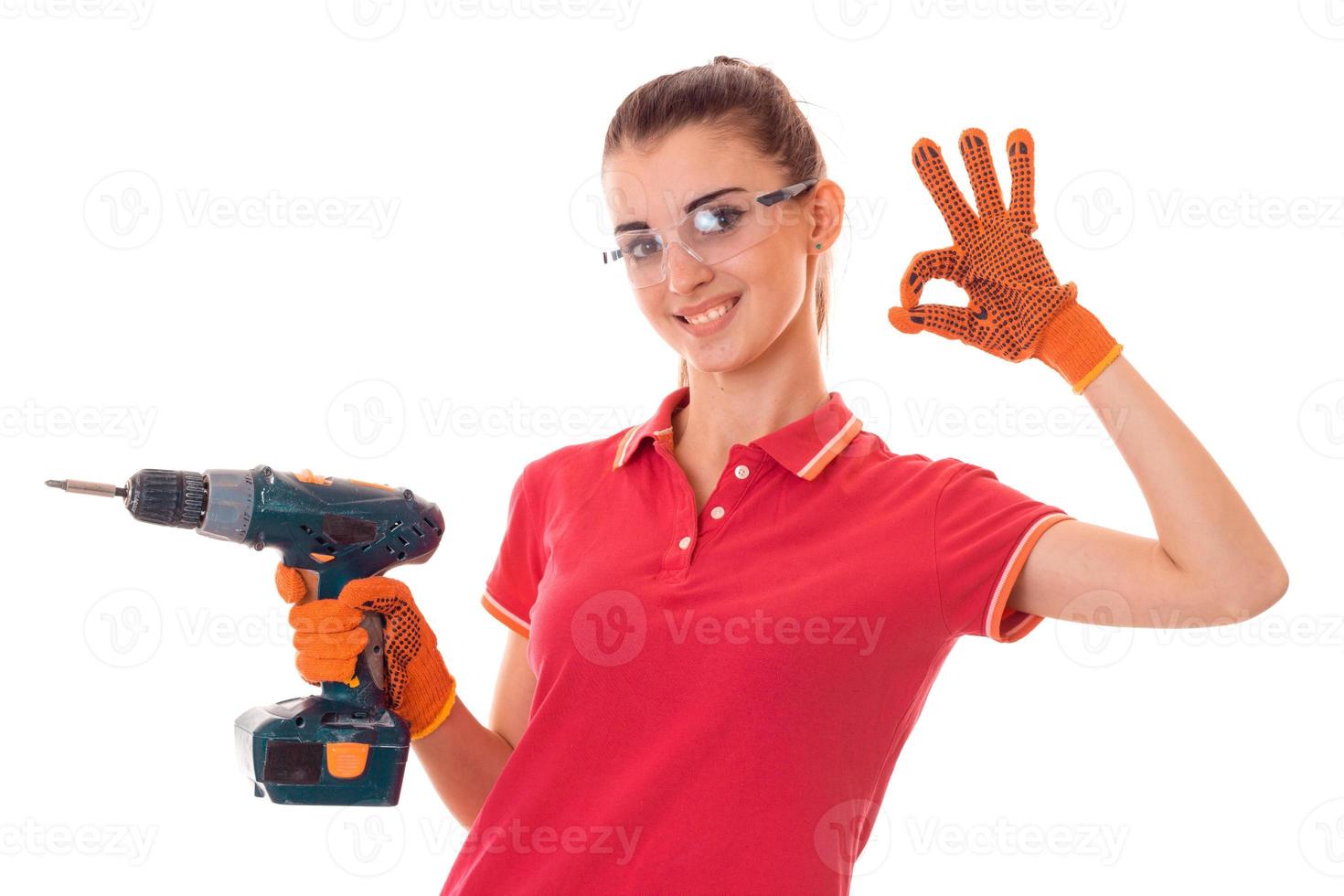 young girl holding a drill for the repair of an apartment and shows the hand gesture photo