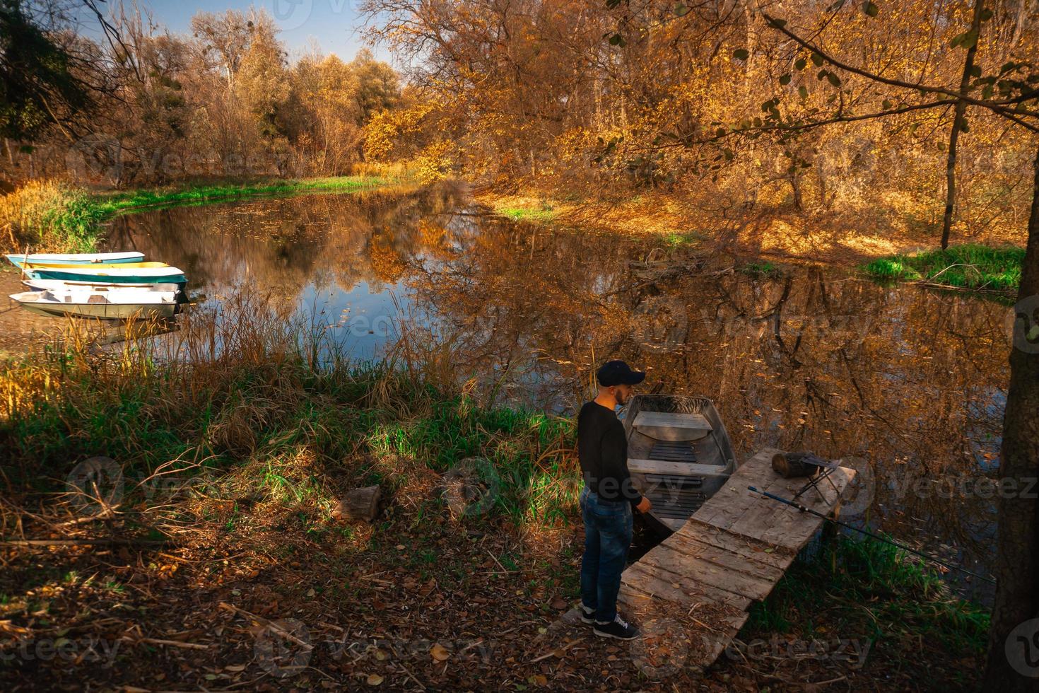 handsome guy stands on the river bank in autumn photo