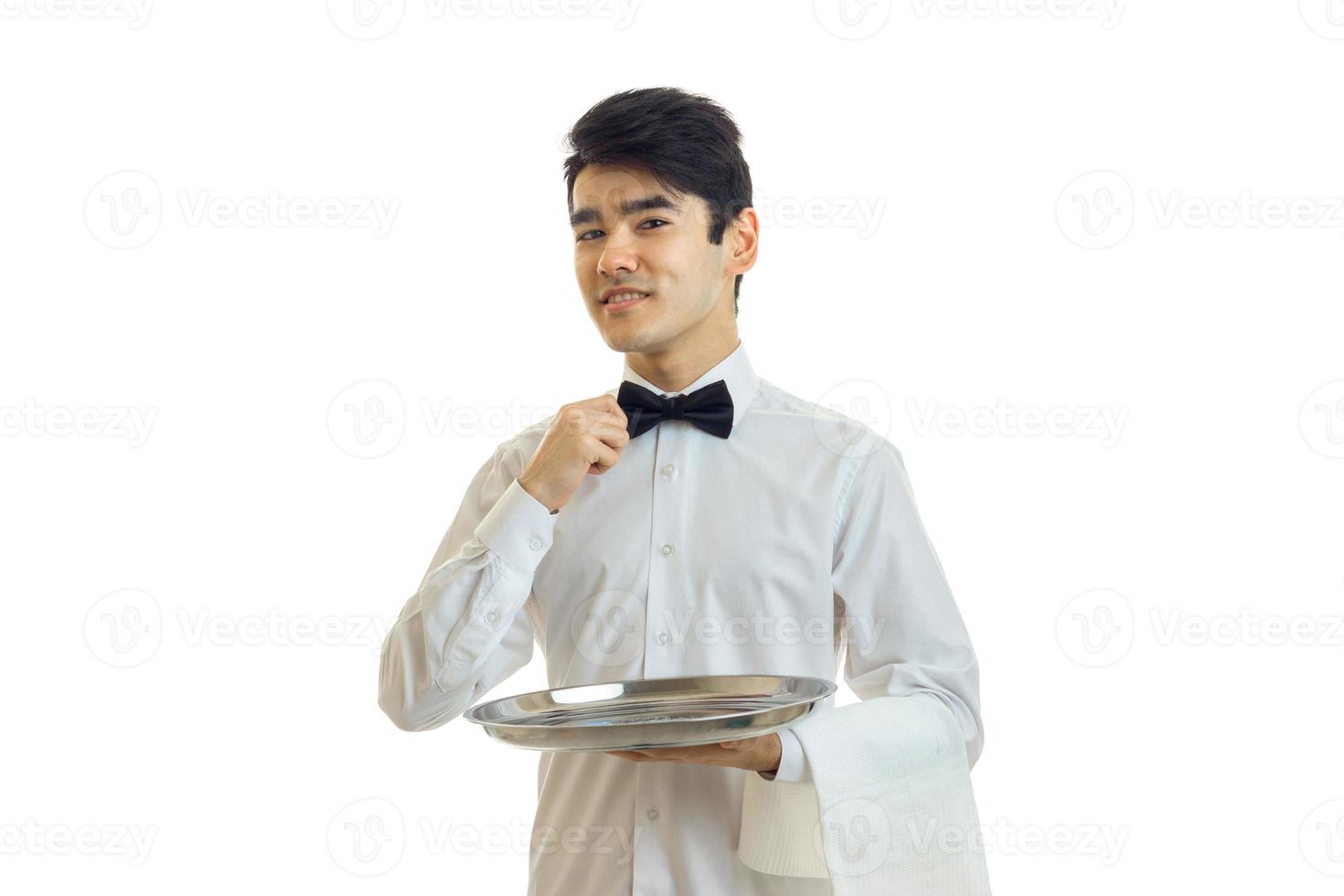 charming waiter in a white shirt holding a tray, and adjusts his bow photo