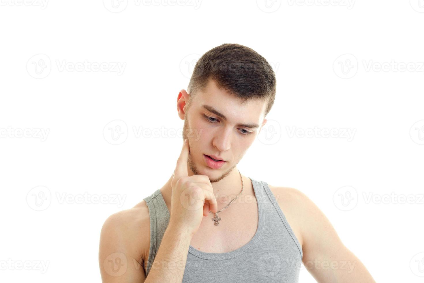 young brooding guy looks down and keeps the finger near the cheeks close-up photo