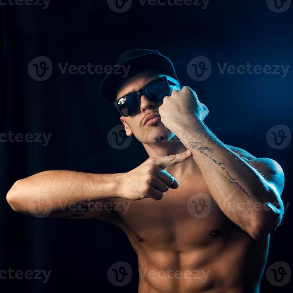 square photo of muscular man with tattoo on arm in studio