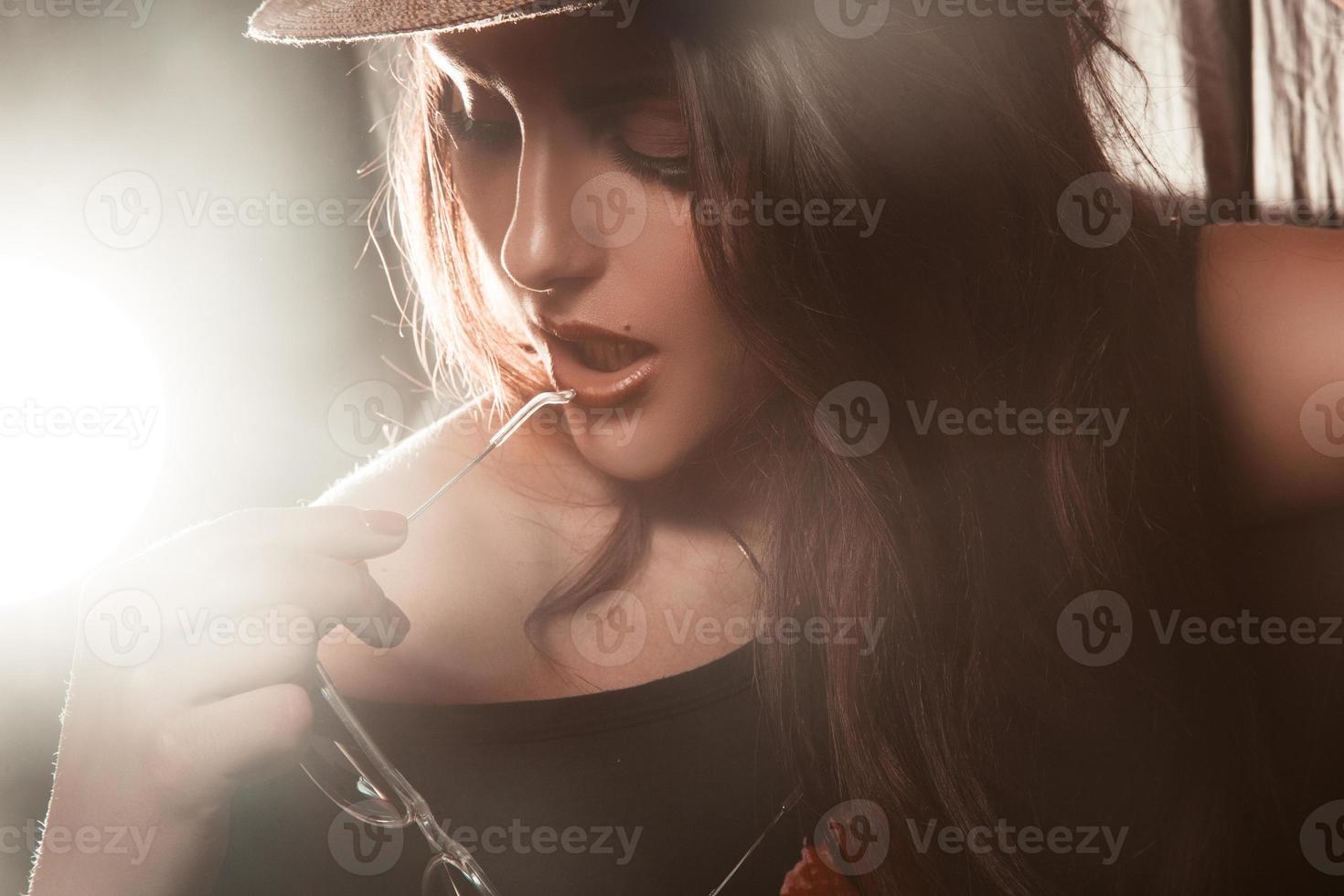 Portrait of adorable young woman in studio with sunglasses in hand photo