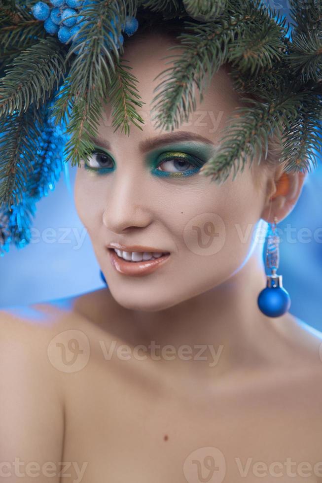 Stunning young girl with xmas tree-wreath on head looking at camera photo