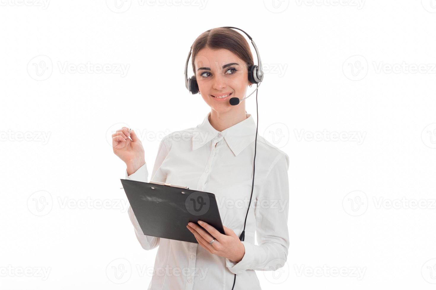 beautiful young brunette business woman with headphones and microphone smiling and make notes isolated on white background photo