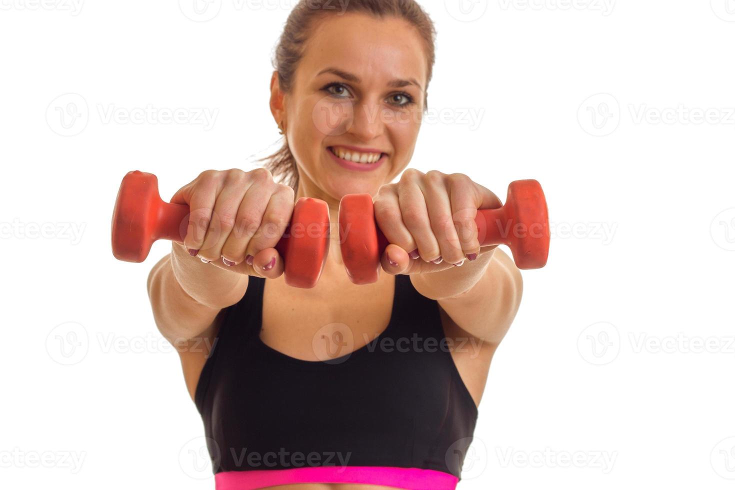 smiling young girl looks arjamo and stretches vpred dumbbells in hands isolated on white background photo