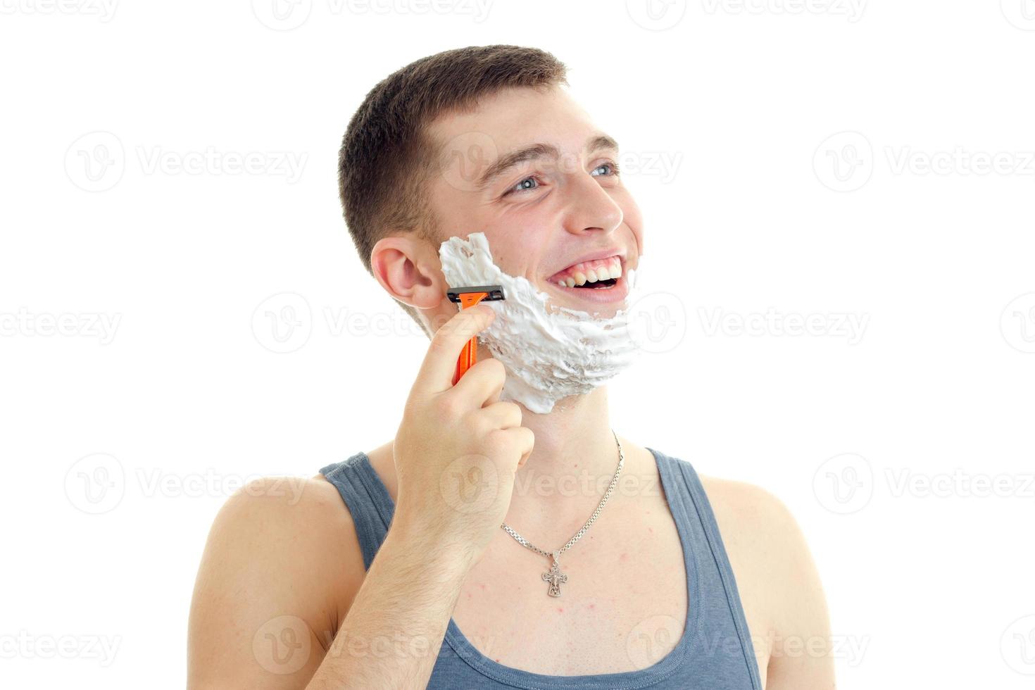 young gay guy with foam on his face looking sideways and shaves photo