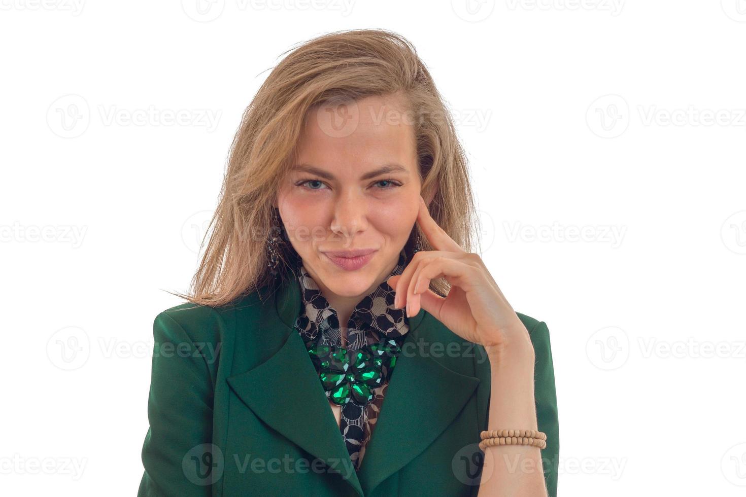 Portrait of a beautiful young girl who looks into the camera keeps a finger near the face and smiling photo