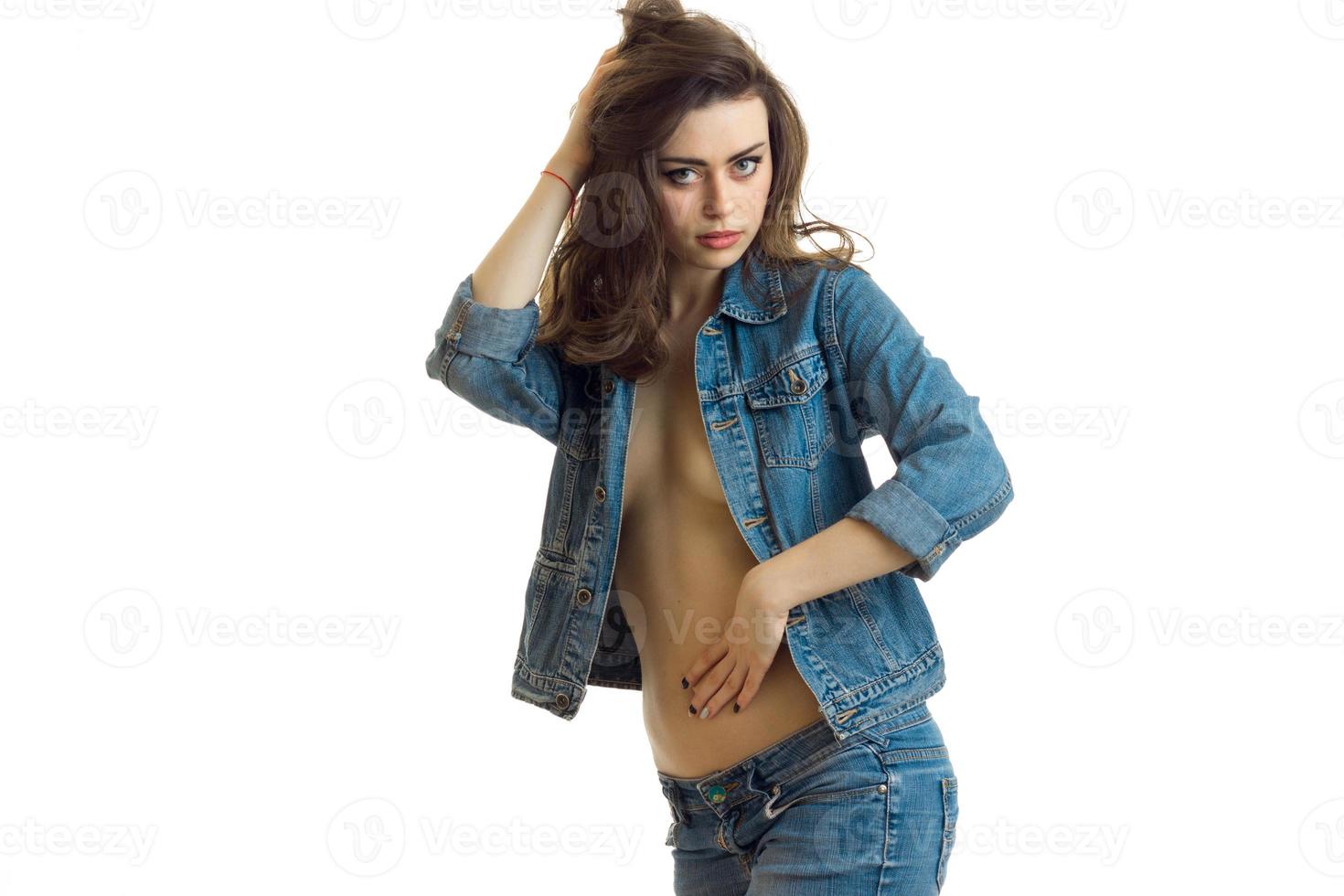 beautiful erotic young girl with denim jacket undone sexually look in camera and holds her hand near the hair photo