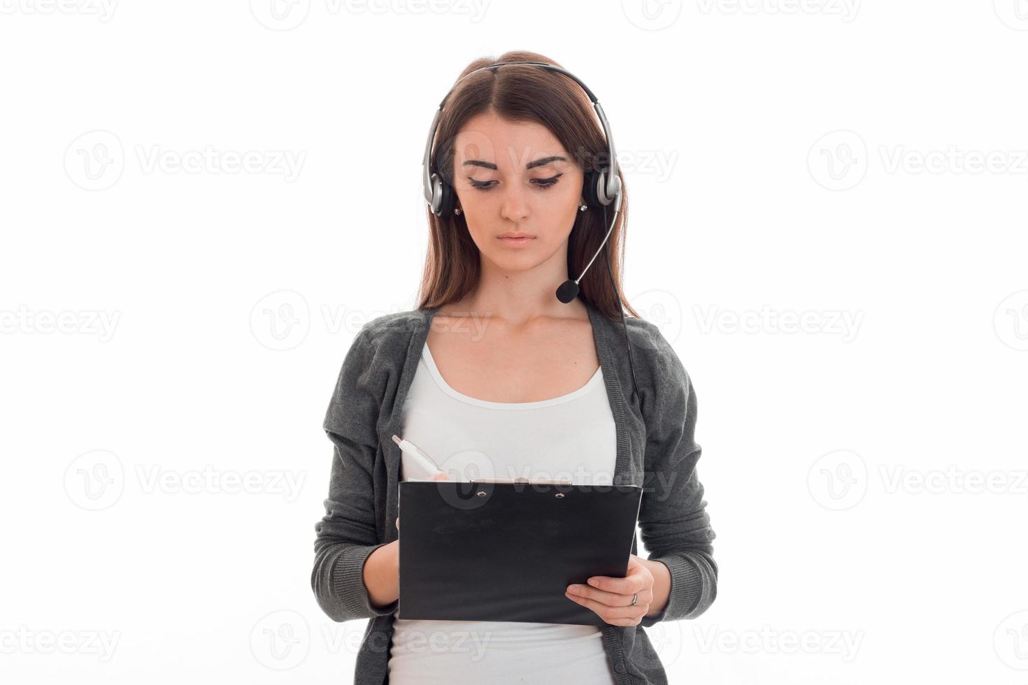 young adorable brunette business woman with headphones and microphone make notes isolated on white background photo