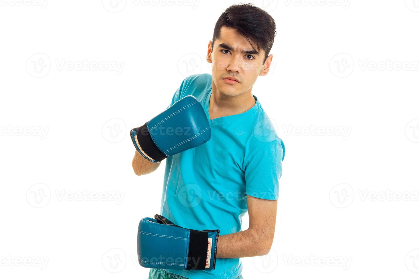 a young guy in a blue shirt and boxing gloves looks in camera photo