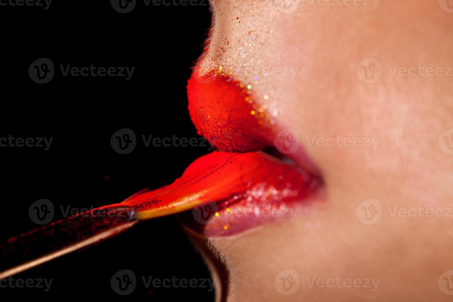 macro photo of Girl applies lipstick with brush in studio