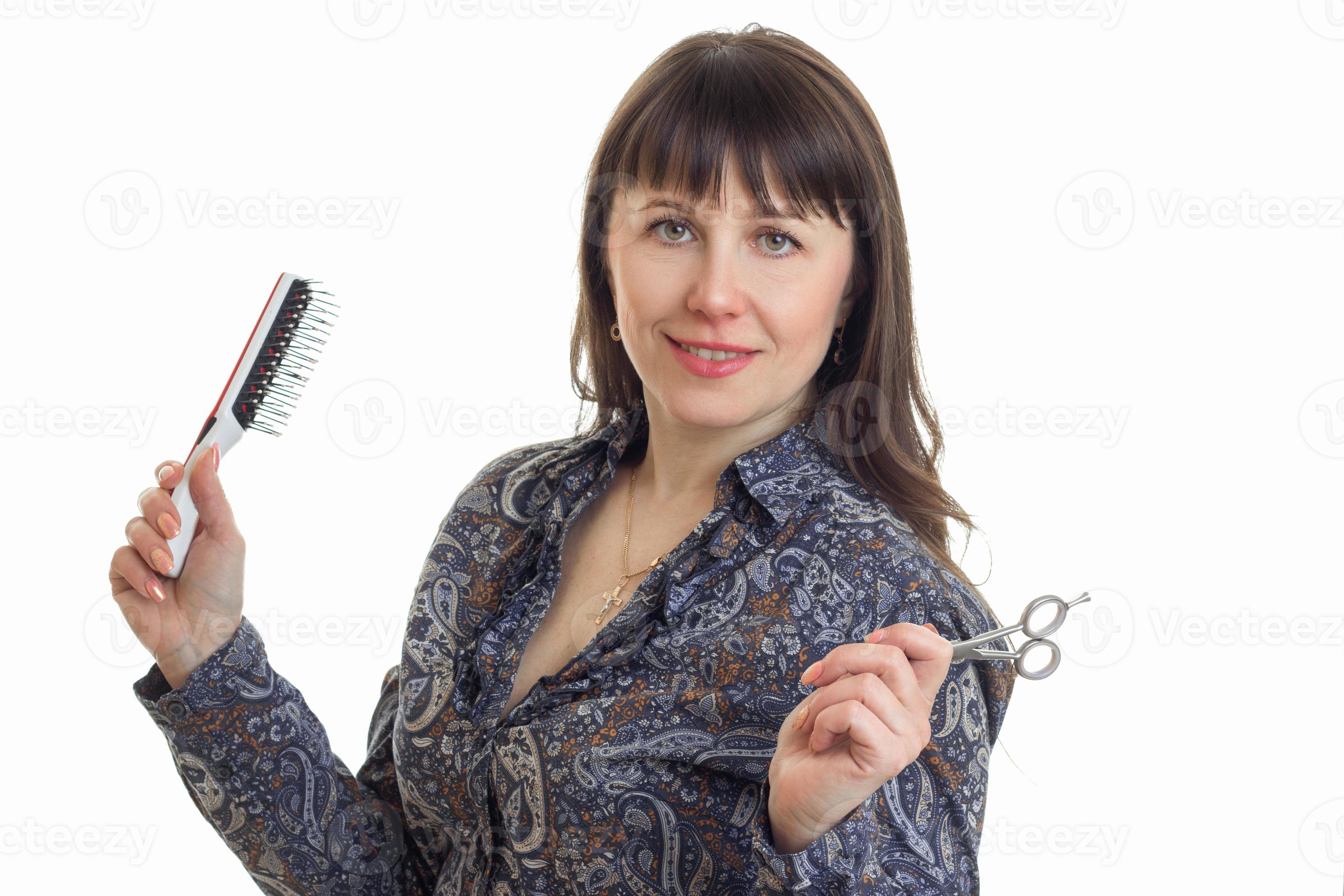 Portrait of a pretty young woman with scissors and comb in the hands