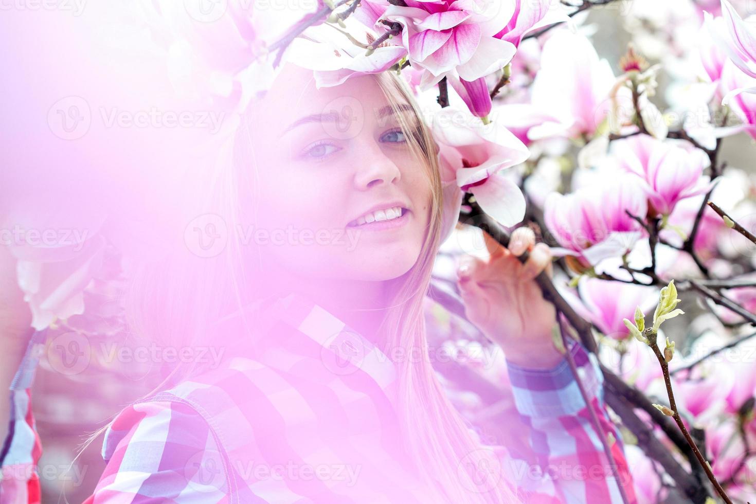 Wonderful young blond woman smiling in pink blooming flowers photo