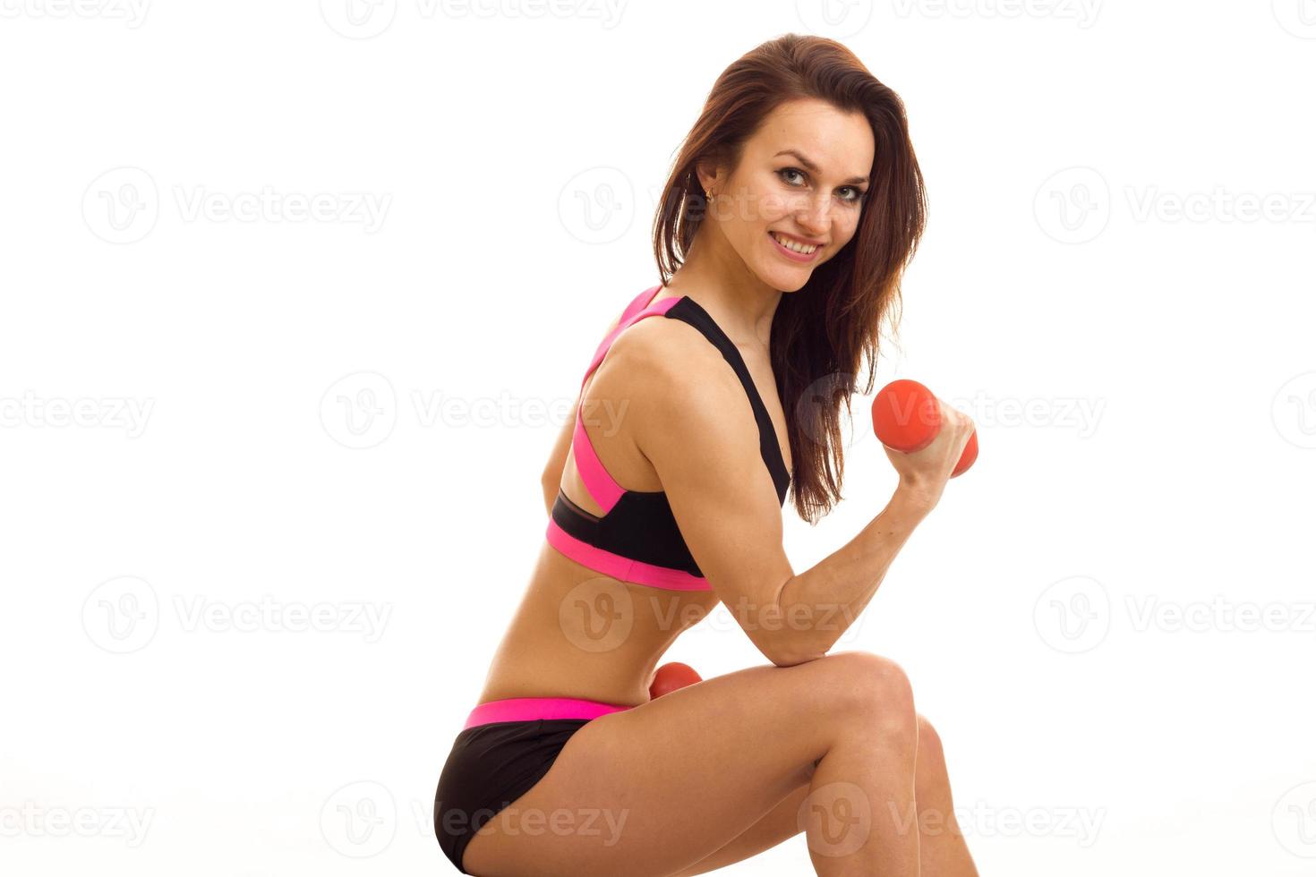 joyful young fitness girl looks straight and holding a dumbbell close-up photo