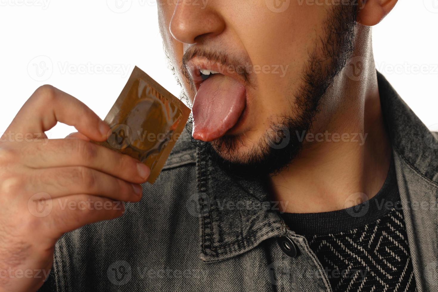 Sexy unshaved gay man with condom in his mouth photo