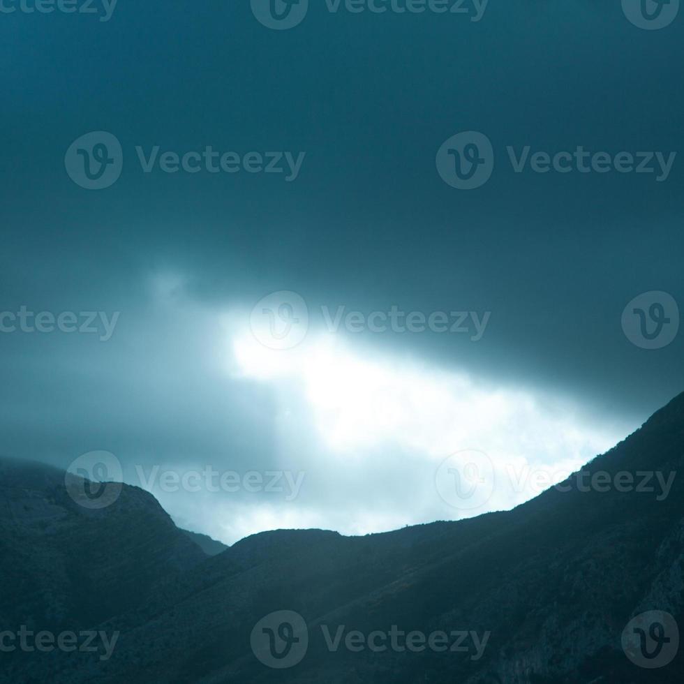 Square photo of dramatic rays of light pushing up through clouds