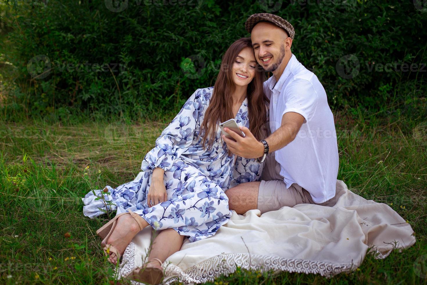 Happy young stylish couple makes selfie on a mobile phone outdoors photo