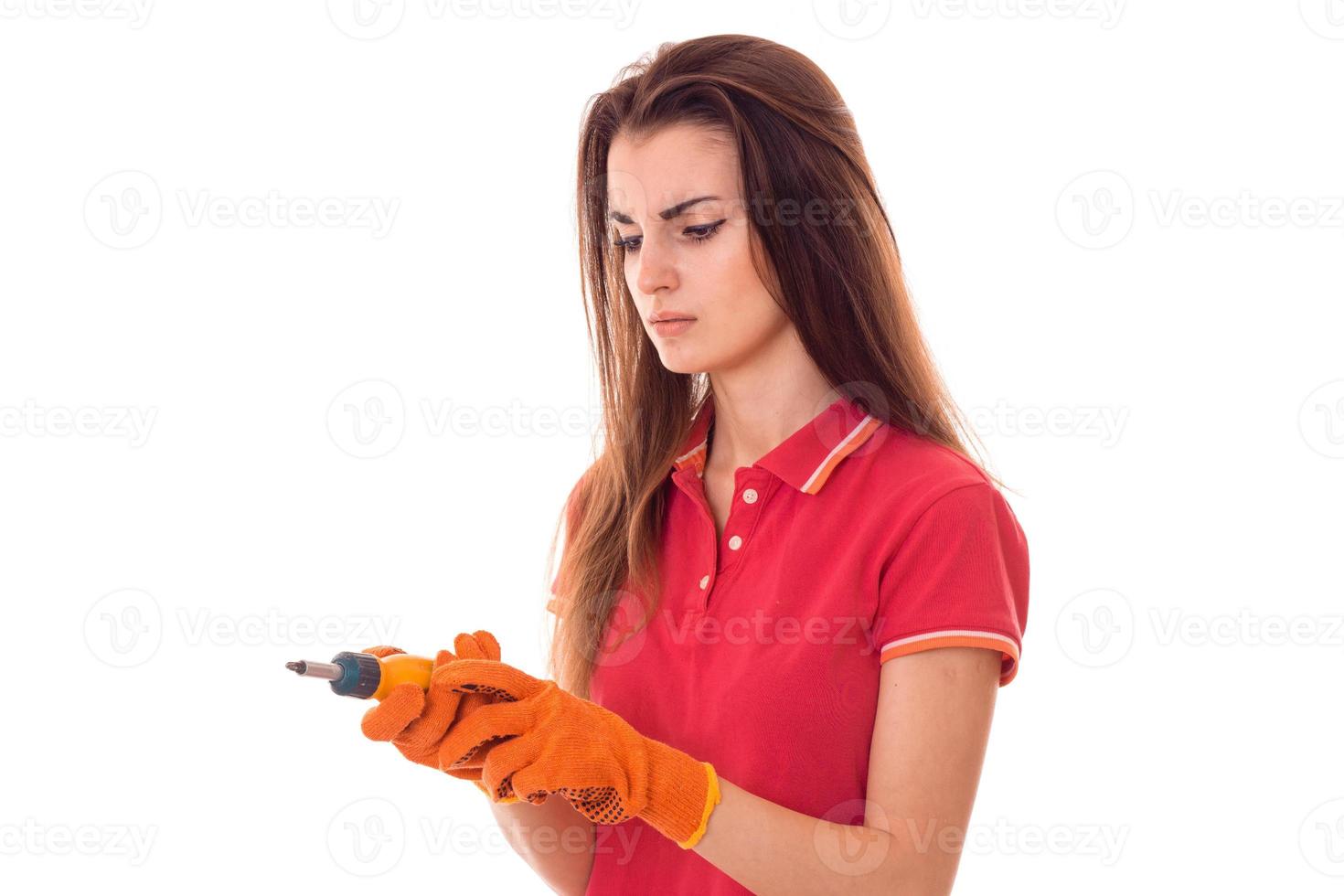 serious young slim builder girl makes renovations with screwdriver isolated on white background photo