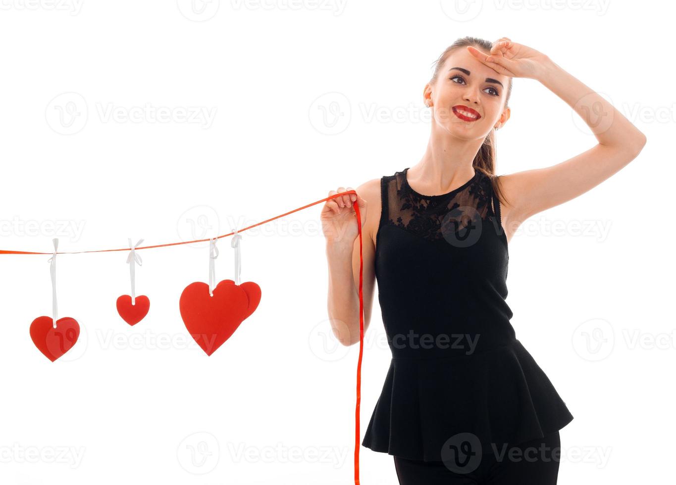 beautiful young girl in black dress holding a Ribbon with cards in the form of hearts photo