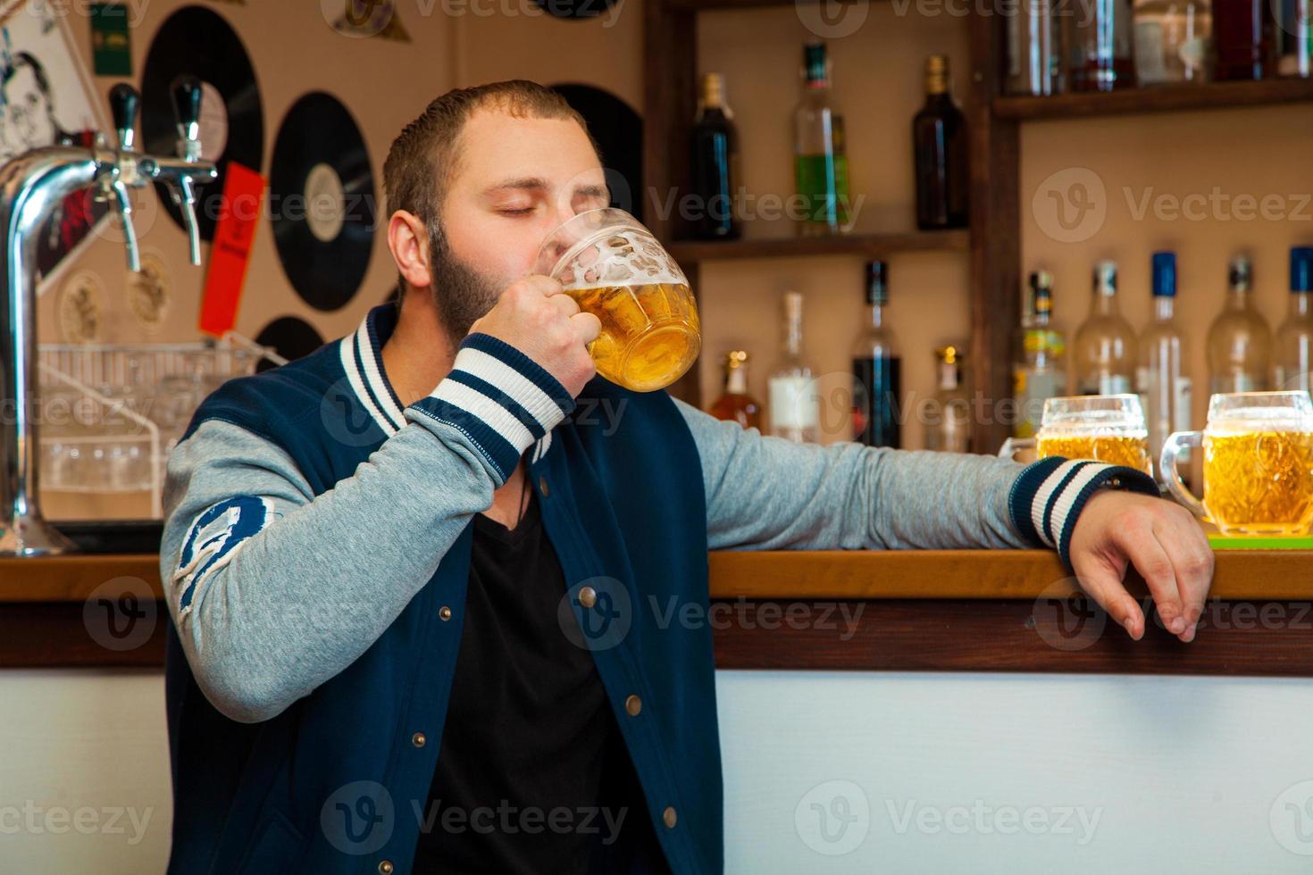 buen hombre en el bar bebe un vaso de cerveza ligera foto