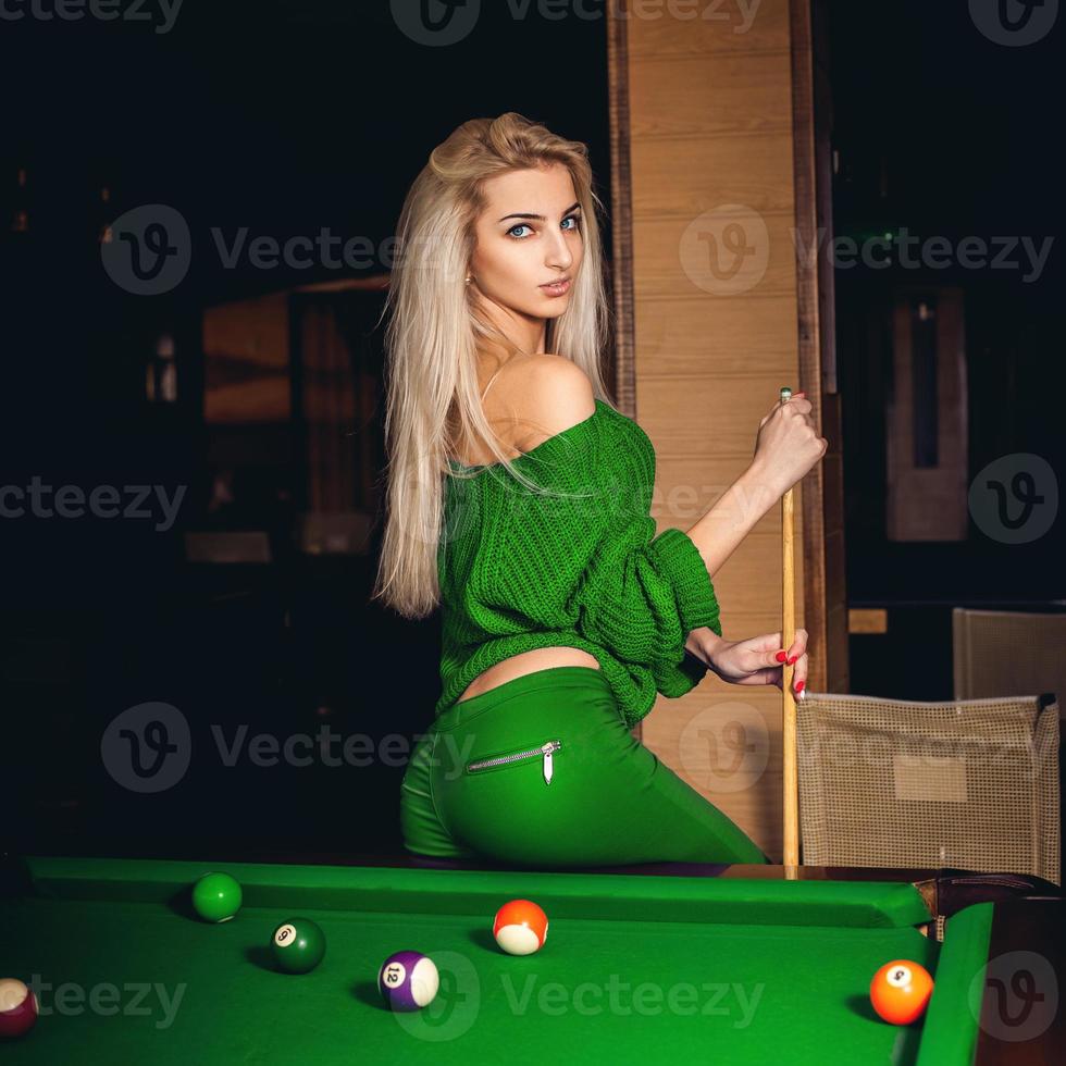 Attractive young blonde lady plays billiard photo